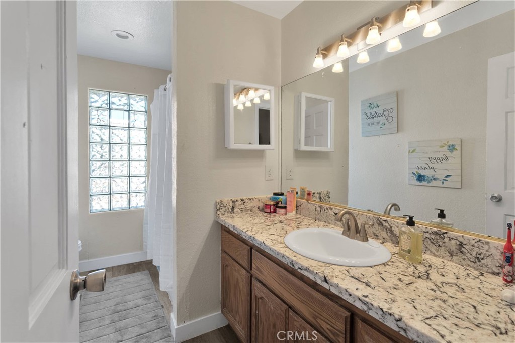 10325 Sheep Creek Road Phelan, CA 92371 - Photo 30 of 47 a bathroom with a granite countertop sink a large mirror and a shower