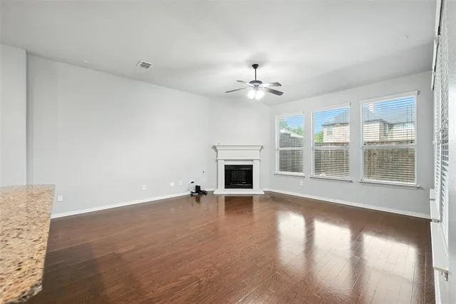 an empty room with wooden floor fireplace and windows