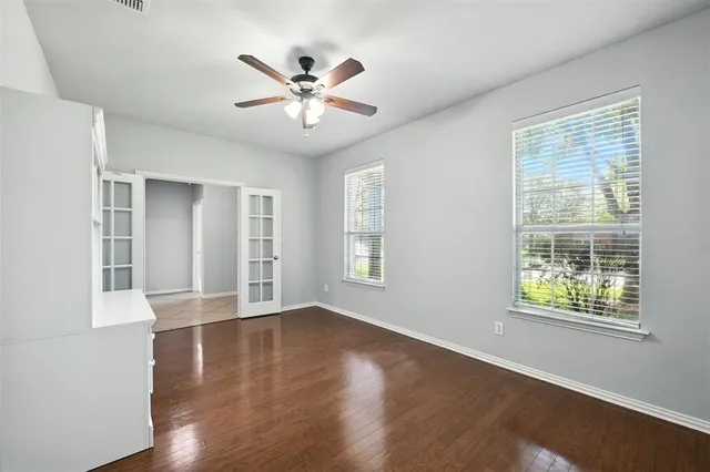 a view of an empty room with wooden floor and a window