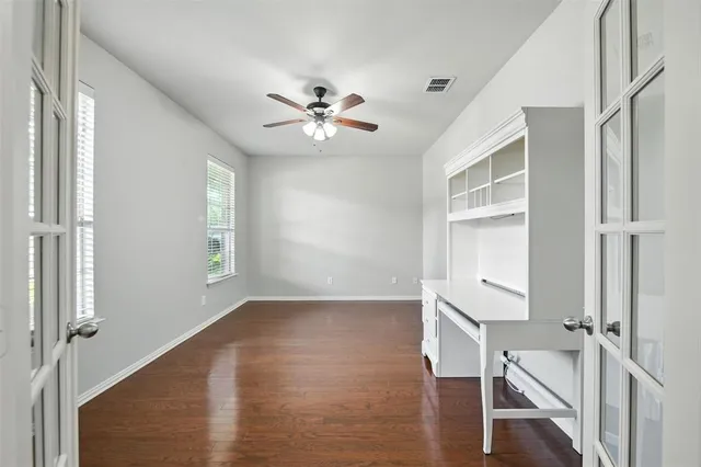a view of empty room with wooden floor and fan