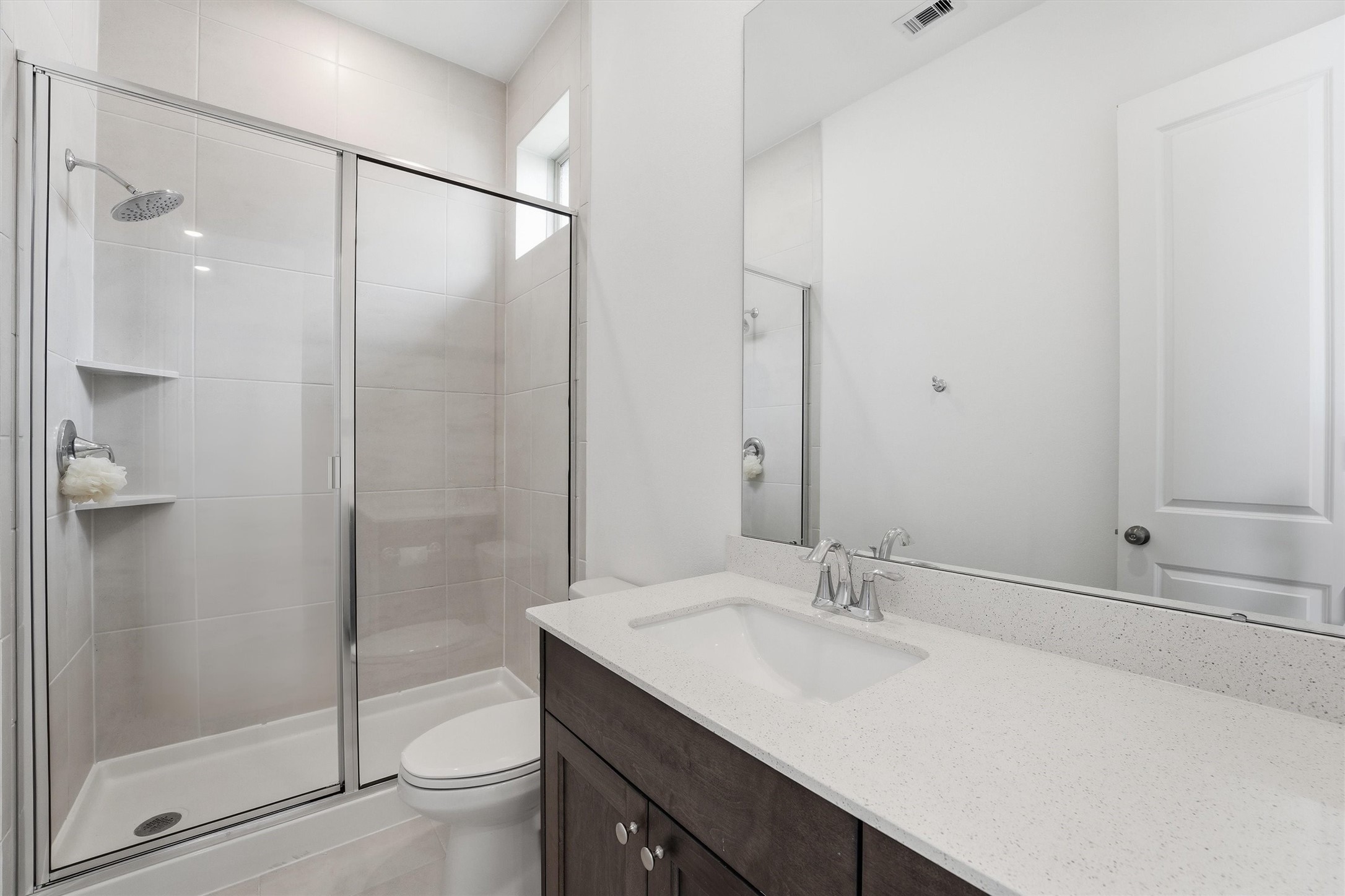 6071 Windward Falls Way Porter, TX 77365 - Photo 10 of 33 This bathroom features a sleek, modern design with a glass-enclosed shower, a spacious vanity with a quartz countertop, and a large mirror. Neutral tones and clean lines create a bright and inviting space.