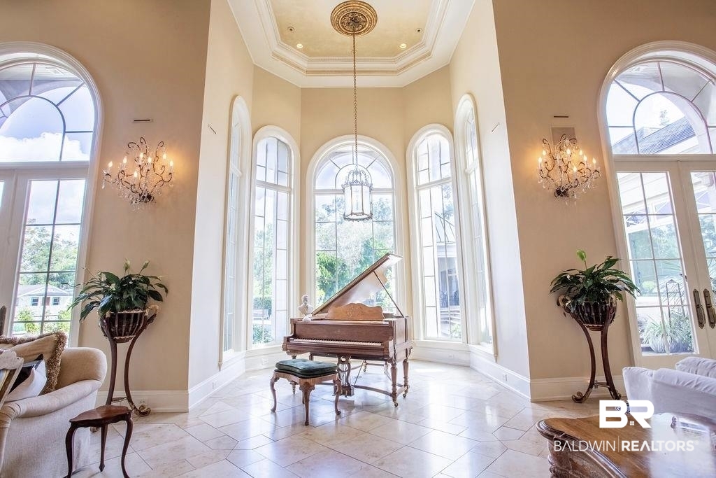 150 Austill Avenue Mobile, AL 36608 - Photo 7 of 39 Two-story foyer featuring arched windows, tile flooring, wall-mounted crystal sconces, and a decorative ceiling medallion with a suspended light fixture
