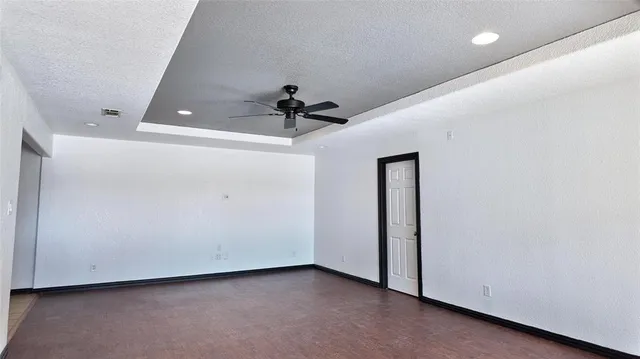 a view of an empty room with a window and wooden floor