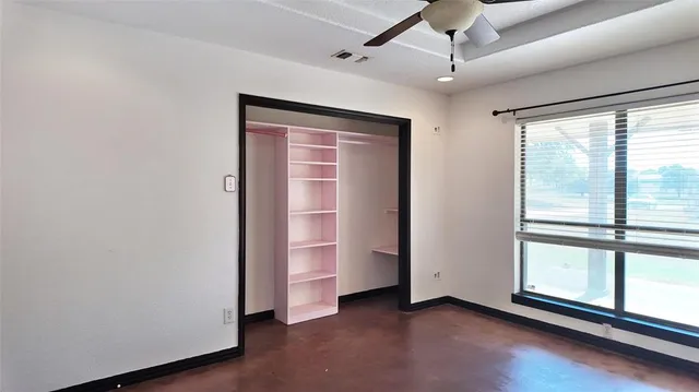 an empty room with a window and a ceiling fan