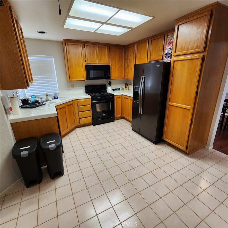 29806 Coral Tree Court Menifee, CA 92584 - Photo 9 of 29 a kitchen with stainless steel appliances a refrigerator and wooden cabinets