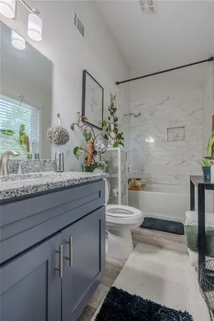 a bathroom with a granite countertop toilet sink and mirror