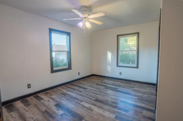 a view of an empty room with window and wooden floor