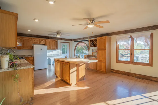 a kitchen with stainless steel appliances granite countertop a refrigerator a sink a stove top oven a dining table and chairs with wooden floor