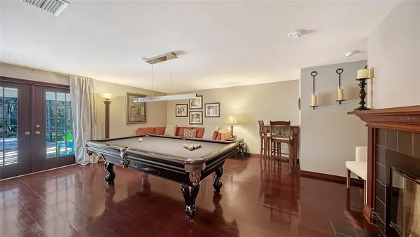 a room with furniture pool table wooden floor and windows