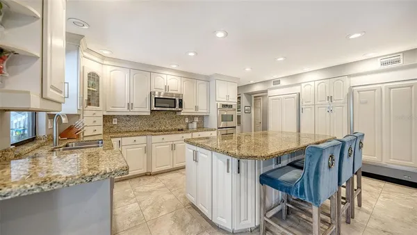 a kitchen with stainless steel appliances granite countertop a table chairs sink and cabinets