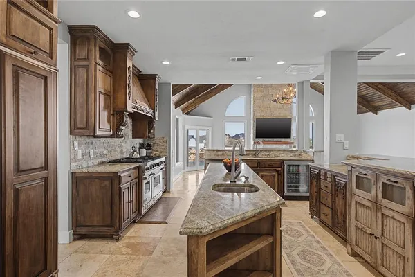 a kitchen with stainless steel appliances granite countertop a stove top oven a sink and a refrigerator