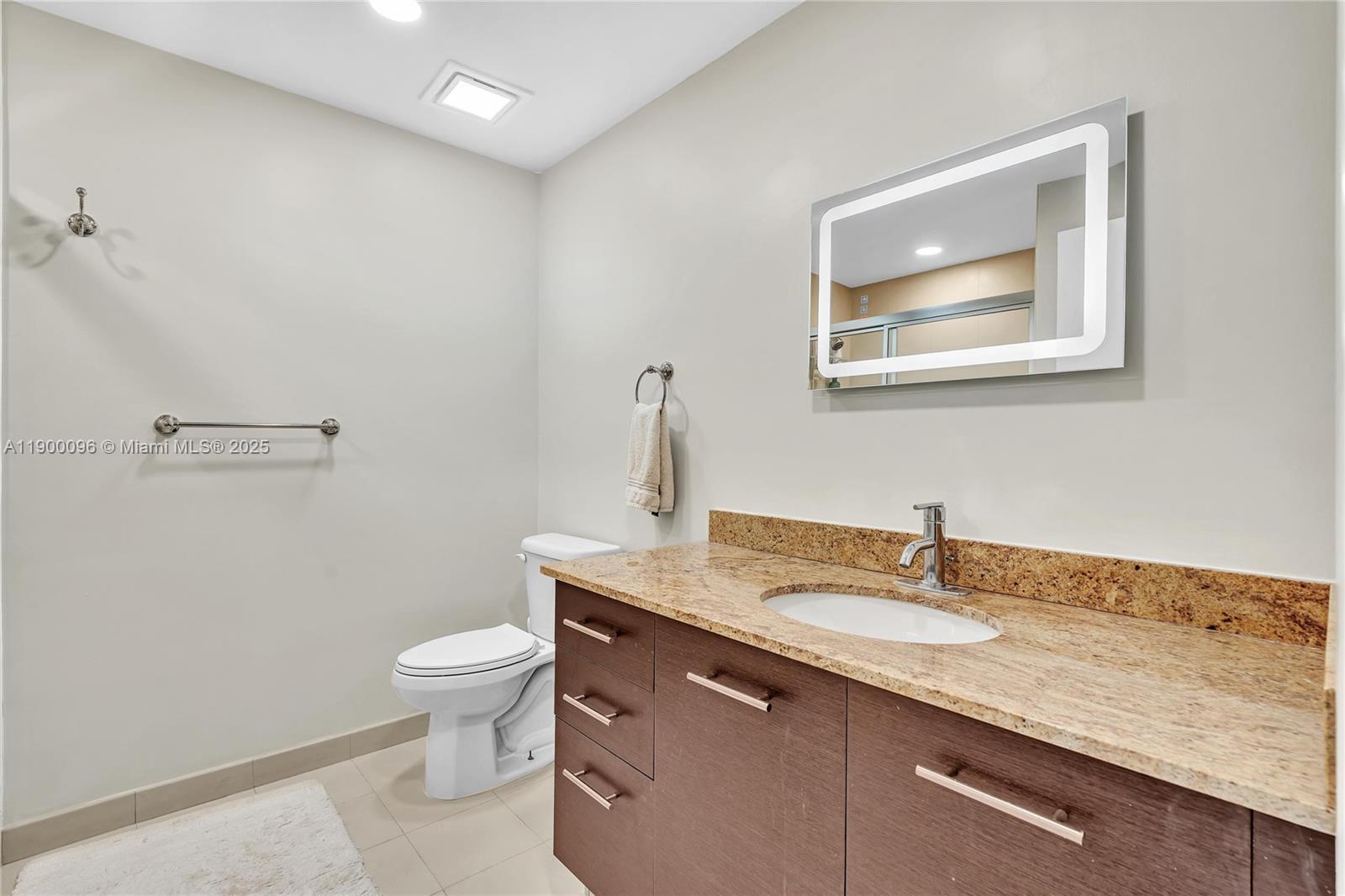 3029 Northeast 188th Street, Unit 503 Aventura, FL 33180 - Photo 39 of 60 a bathroom with a granite countertop sink a toilet and mirror