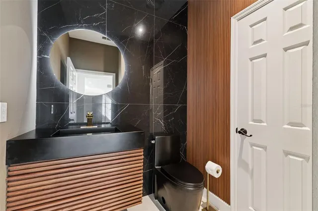 a kitchen with stainless steel appliances granite countertop a sink a stove and chairs with wooden floor