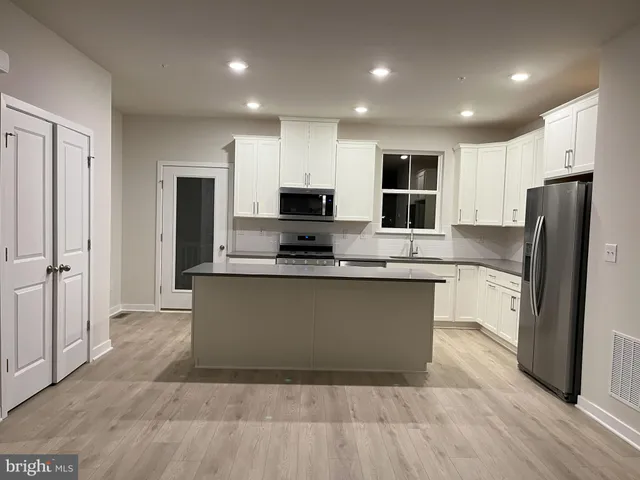 a large kitchen with stainless steel appliances granite countertop a refrigerator and a stove top oven