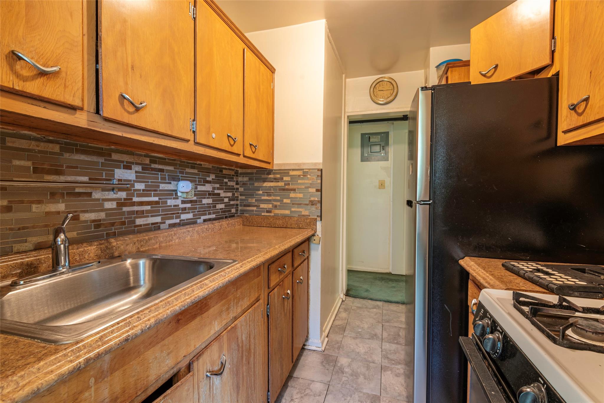 99-35 59th Avenue, Unit 4K Queens, NY 11368 - Photo 13 of 24 Kitchen with white gas range, a sink, tasteful backsplash, brown cabinets, and light tile patterned flooring