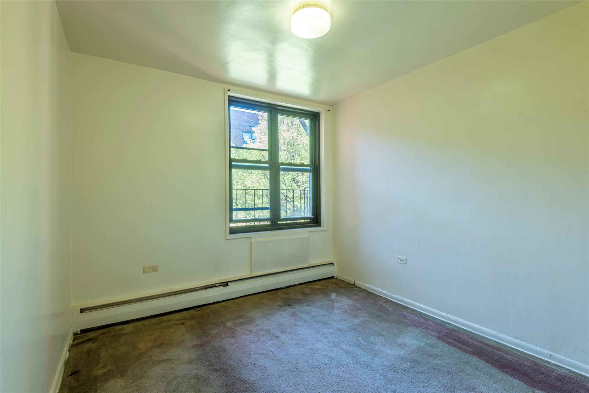 99-35 59th Avenue, Unit 4K Queens, NY 11368 - Photo 16 of 24 Carpeted spare room with baseboard heating and baseboards