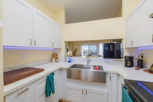 a kitchen with a sink dishwasher a stove and a dining table with wooden floor