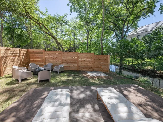 a view of a backyard with table and chairs potted plants and large trees