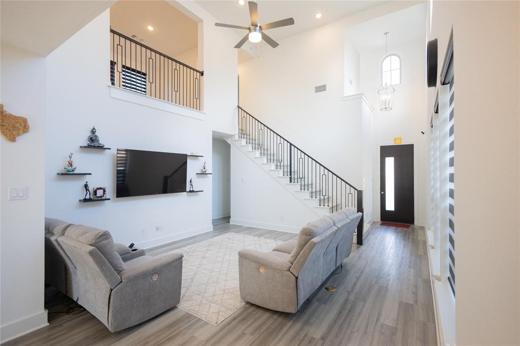 3017 Andorra Road McKinney, TX 75071 - Photo 7 of 40 Soaring ceilings, wood-finish flooring, and a contemporary open-tread staircase with black wrought iron railings