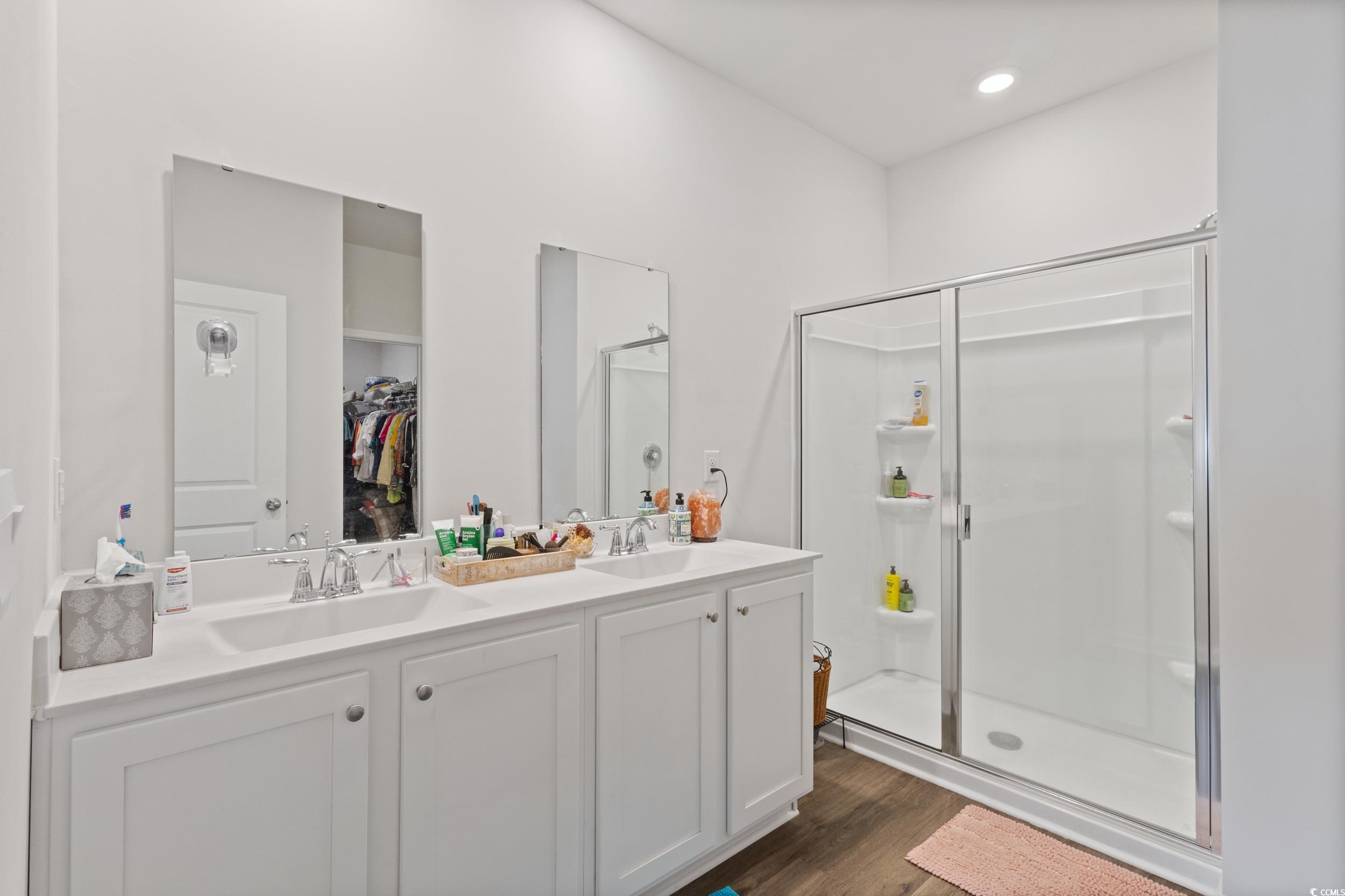 8034 Strudwick Drive Little River, SC 29566 - Photo 22 of 36 Full bathroom featuring a shower stall, double vanity, a spacious closet, and dark wood-style flooring