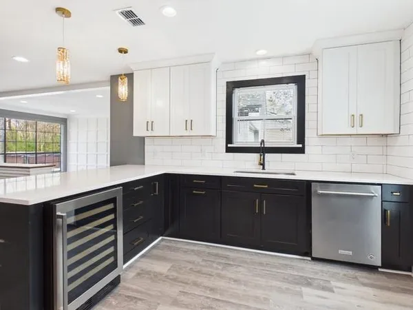 a kitchen with stainless steel appliances granite countertop a sink dishwasher a stove and white cabinets with wooden floor