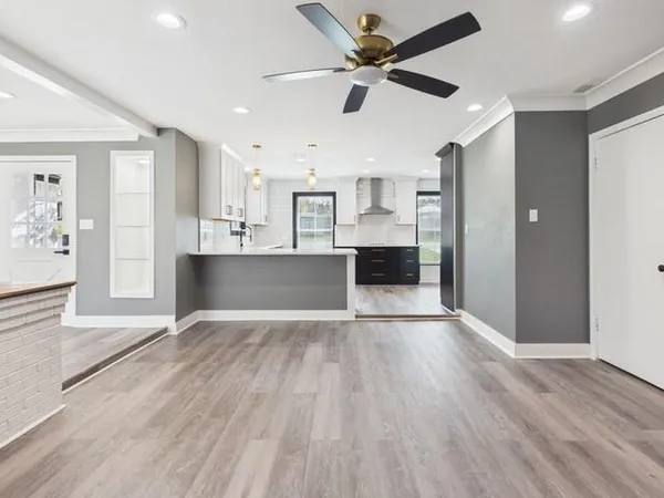 a view of kitchen and empty room with wooden floor