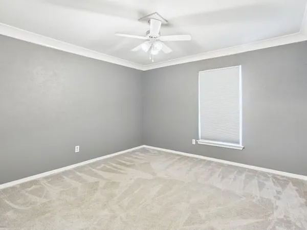 an empty room with a chandelier fan and windows