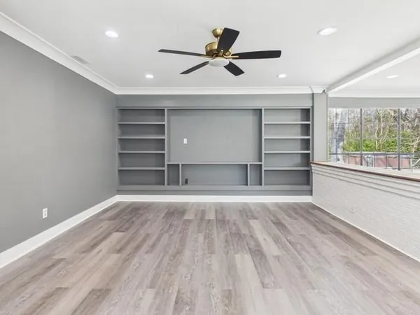a view of an empty room with a window and wooden floor