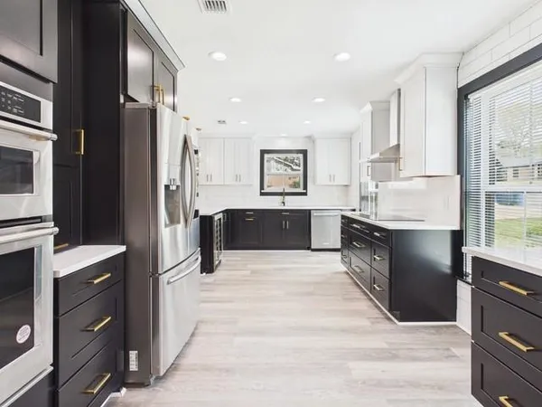 a large kitchen with stainless steel appliances kitchen island granite countertop a refrigerator and a stove top oven