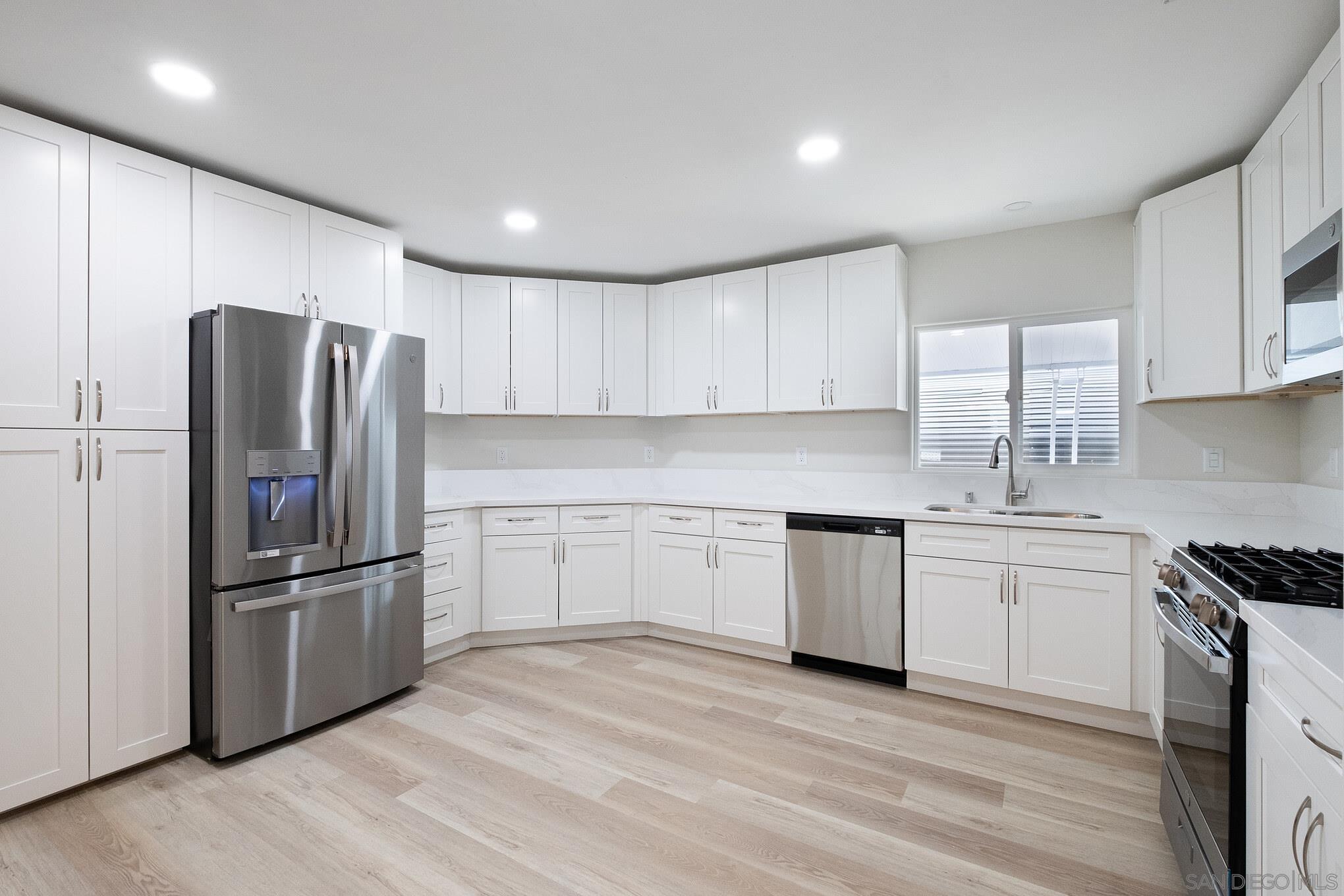 a kitchen with granite countertop stainless steel appliances a refrigerator sink and cabinets