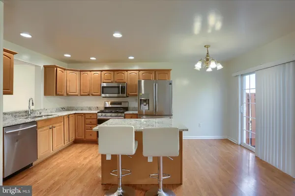 a kitchen with stainless steel appliances granite countertop a stove top oven a sink and a refrigerator