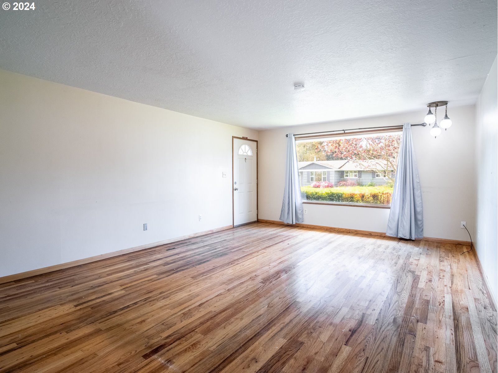 3238 Southeast 176th Place Portland, OR 97236 - Photo 5 of 31 a view of an empty room with a window and wooden floor
