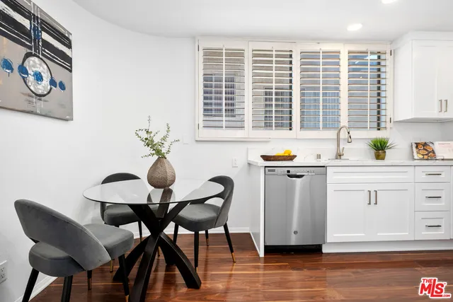 a kitchen with stainless steel appliances granite countertop a table chairs and a refrigerator