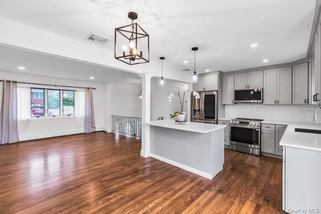 a kitchen with stainless steel appliances granite countertop a refrigerator a stove top oven a sink dishwasher and white cabinets with wooden floor
