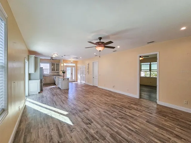 wooden floor in an empty room with a chandelier fan