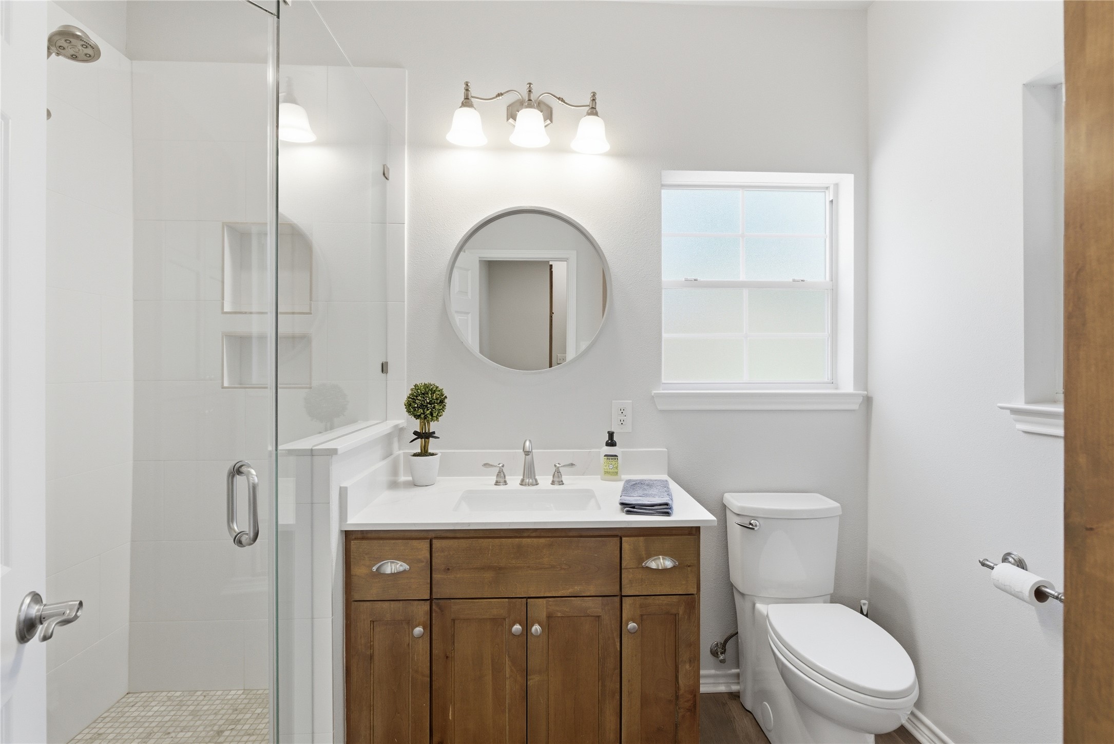 1204 Orlando Road Austin, TX 78733 - Photo 32 of 40 A well-lit bathroom with a glass-enclosed shower and wood vanity.