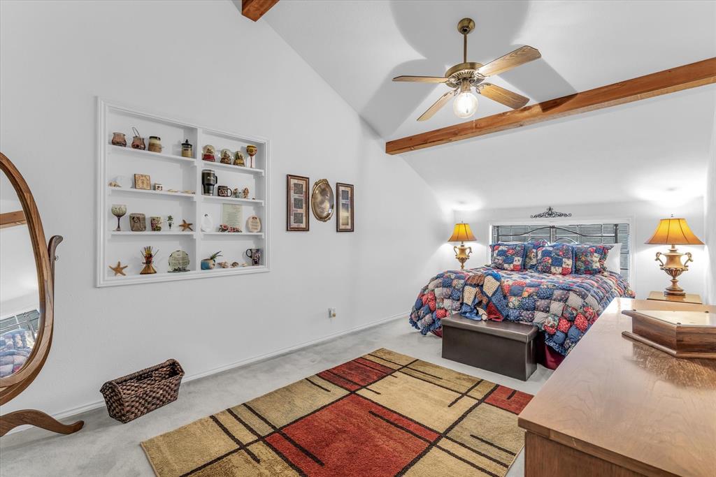 1438 Bend Of The Bosque Road China Spring, TX 76633 - Photo 8 of 33 Vaulted ceiling with exposed wood beams, ceiling fan, built-in shelving, and carpeted flooring