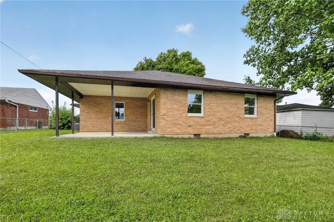 1243 Student Avenue Springfield, OH 45503 - Photo 37 of 38 A deep covered patio stretches across the brick exterior bordering a grassy lawn.