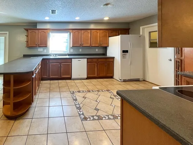 a open kitchen with stainless steel appliances granite countertop a refrigerator and a stove top oven