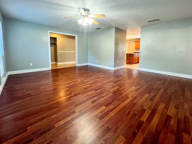 a view of empty room with wooden floor and fan