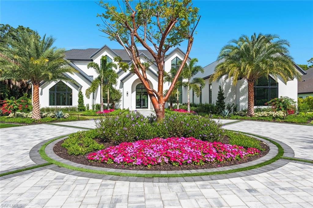 2145 Coach House Lane Naples, FL 34105 - Photo 2 of 9 a view of a white house with a flower garden