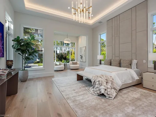 a spacious bedroom with a bed a chandelier and a couch