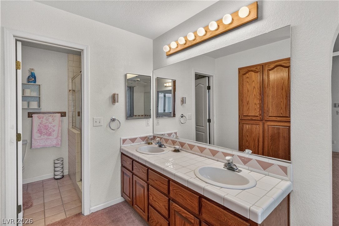 2055 Cholla Way Laughlin, NV 89029 - Photo 36 of 87 Double vanities with tile counters and a wood cabinet offer convenience in this well-appointed bathroom.