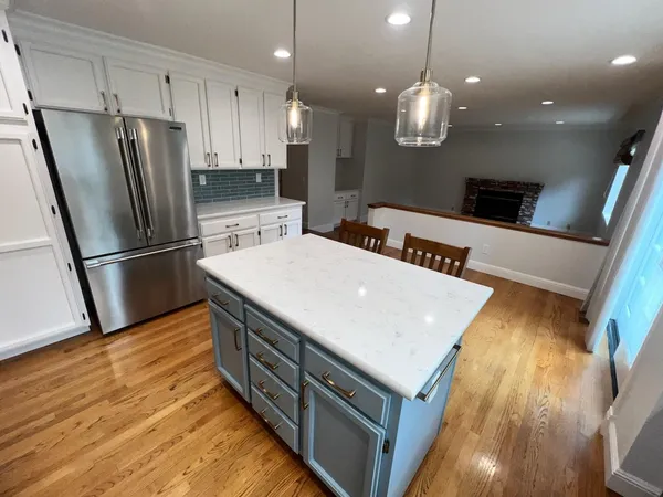 a kitchen with stainless steel appliances a stove a refrigerator a sink and white cabinets with wooden floor