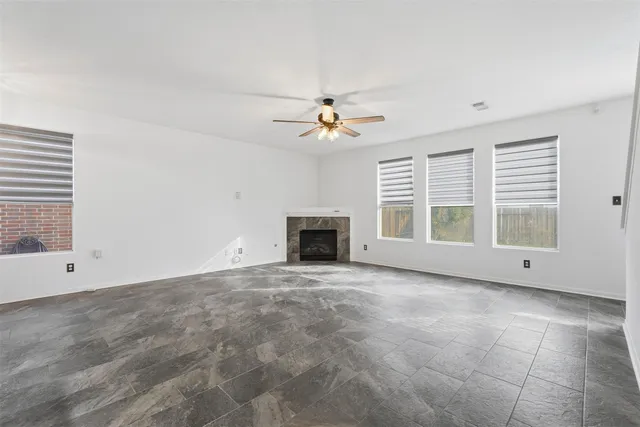 an empty room with windows and ceiling fan