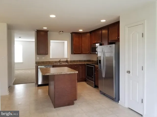 a kitchen with kitchen island stainless steel appliances a sink stove and refrigerator