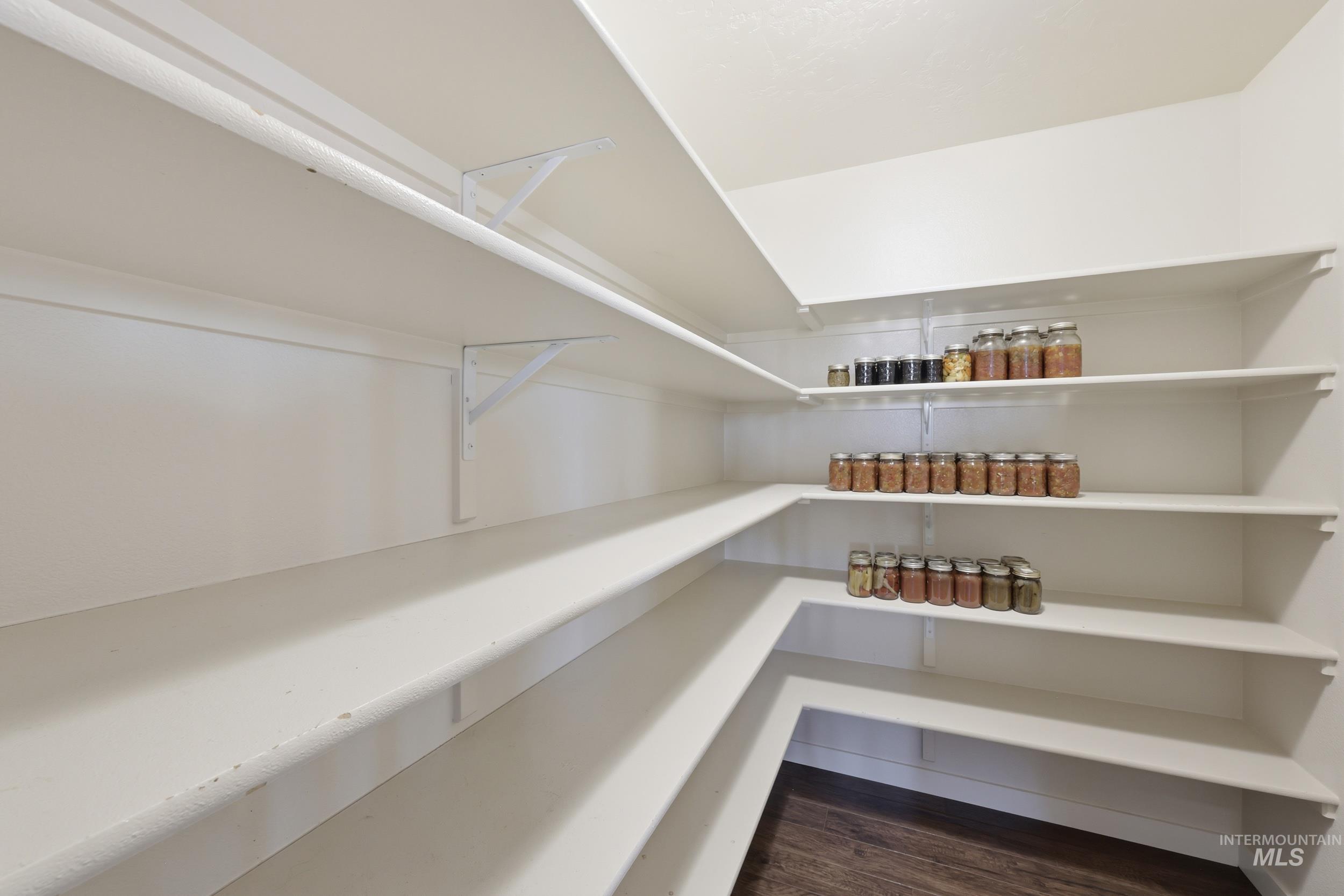 4855 South Chex Way Boise, ID 83709 - Photo 18 of 47 Expansive walk-in pantry featuring multiple levels of white shelving, L-shaped shelving configuration, and wood-finish flooring
