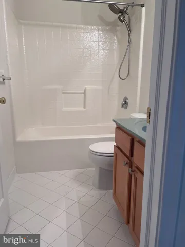a bathroom with a granite countertop bathtub shower sink vanity and toilet
