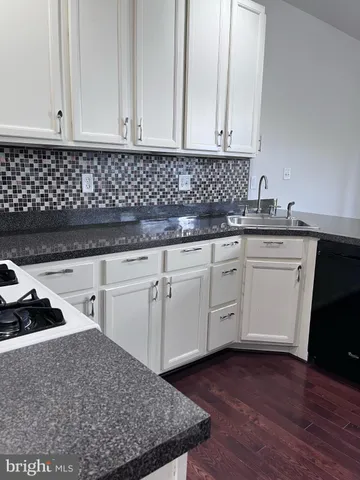 a kitchen with granite countertop white cabinets and sink