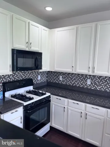a kitchen with granite countertop white cabinets and black appliances